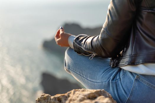 yoga, gesture and healthy lifestyle concept - hand of meditating yogi woman showing gyan mudra over sea sunset background.