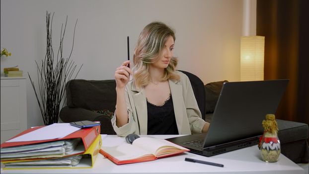 Young business woman working on project paperwork. Female manager making business notes on notebook, working alone in office.