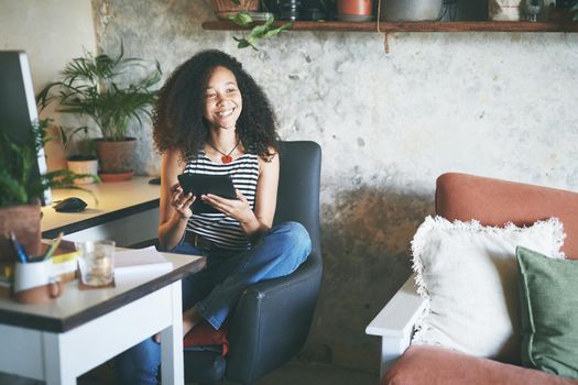 Shot of an attractive young african woman sitting alone and using her tablet while working from home stock photo