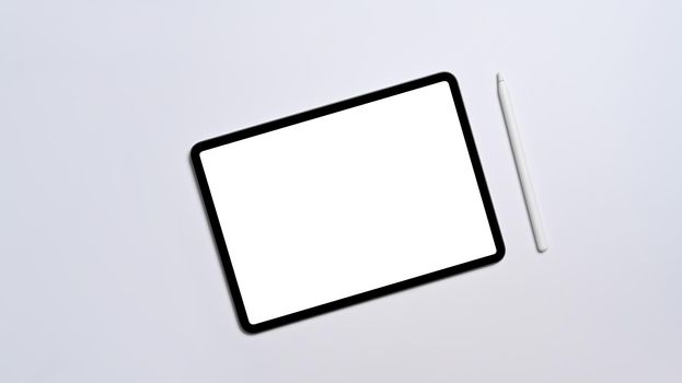 Flat lay digital tablet with empty display and stylus pen on white background.