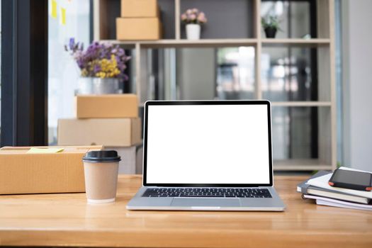 Front view laptop computer, coffee cup and cardboard boxes on wooden table.