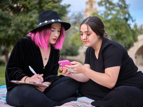 girl showing another girl a halloween drawing with her mobile phone, horizontal blurred background