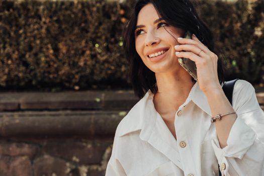 Cheerful Young Brunette Woman Making Phone Call on Smartphone Outdoors, Copy Space