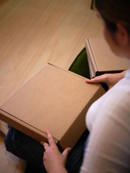 working woman sitting down opening her new product to show it off, view from above