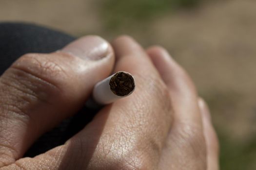 Man hand holding a cigarette, inside close up
