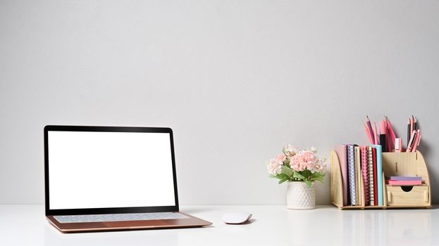 Laptop computer with empty screen and supplies on white table.