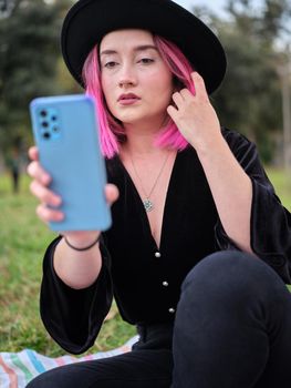 woman posing while looking at her mobile phone and touching her pink hair, vertical close up