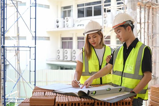 Female architects discussing with engineer about their project at construction site.