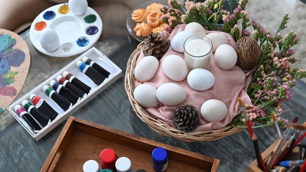 Wicker basket with eggs and spring flowers on wooden table. Easter celebration concept.