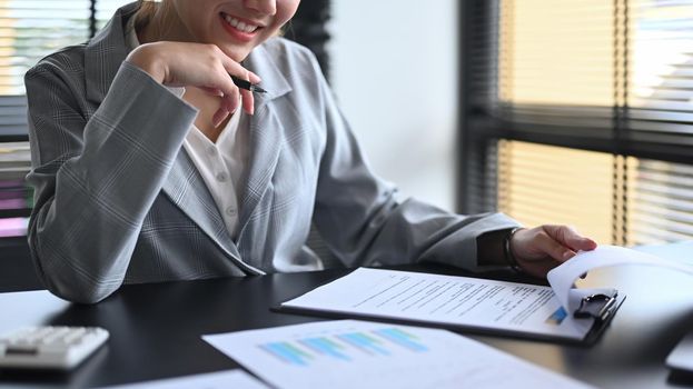 Female accountant analyzing financial document at office desk.