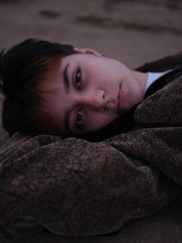 girl with septum piercing and red fringes lying down looking sideways at camera, vertical portrait