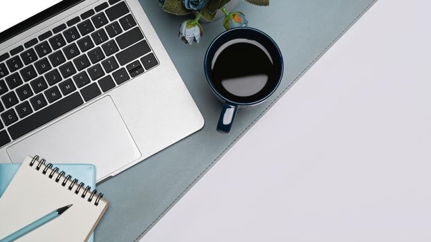 Flat lay computer laptop, coffee cup, notepad and potted plant on white table.