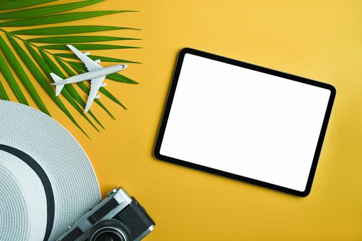 Digital tablet and traveler accessories on yellow background. Travel, summer and holiday concept.