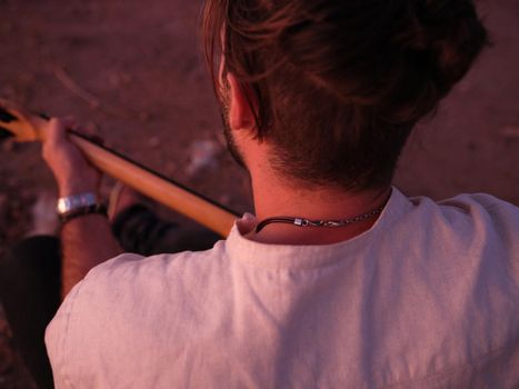 cut out view from behind of a seated man playing the guitar, horizontal close up