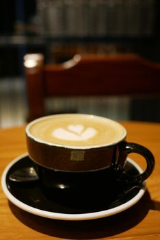 a cup of late coffee with flower shape design on top at cafe .