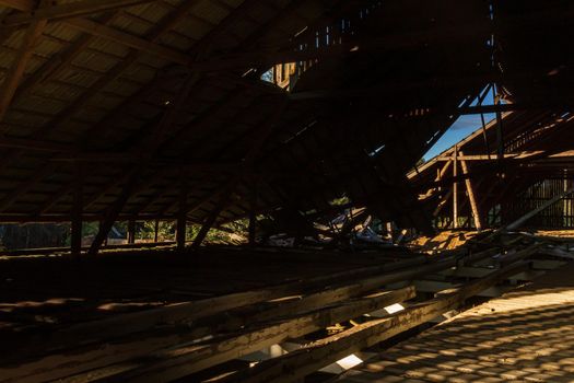 Old farm building underconstruction roof top room, sunshine on the wood floor and broken roof