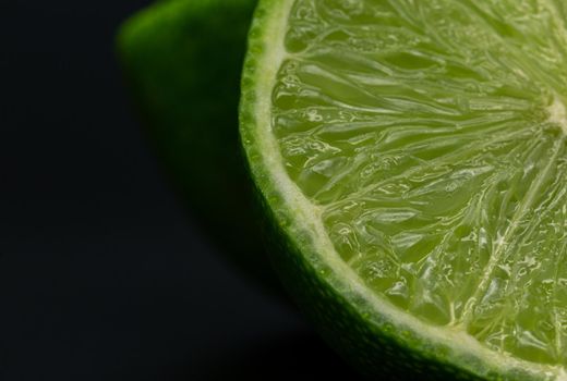 Green lime citruss fruit cutting half macro fiber inside, black background