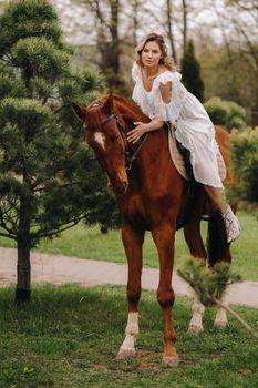 A woman in a white sundress riding a horse near a farm.