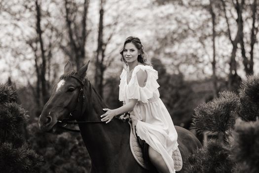 A woman in a white sundress riding a horse near a farm. black and white photo.