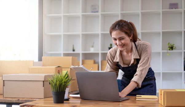 Beautiful smart Asian young entrepreneur business woman owner of SME checking product on stock and write on clipboard working at home. Small business owner at home office concept..