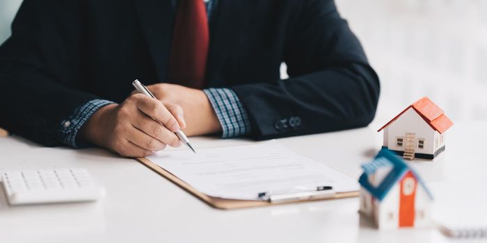 Close up of Businessman pointing and signing agreement for buying house. Bank manager concept