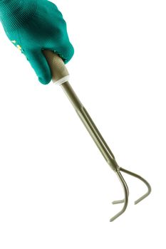 Small garden rake in hand dressed in a green glove isolated on white