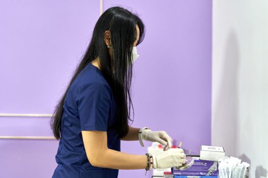 Asian doctor in uniform and mask preparing injections for a skin rejuvenation session for a patient