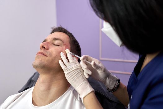 Male patient closing eyes while undergoing a facial rejuvenation treatment with botox injection