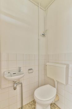 Modern flush toilet and ceramic sink installed on white tiled walls and towel in small restroom at home