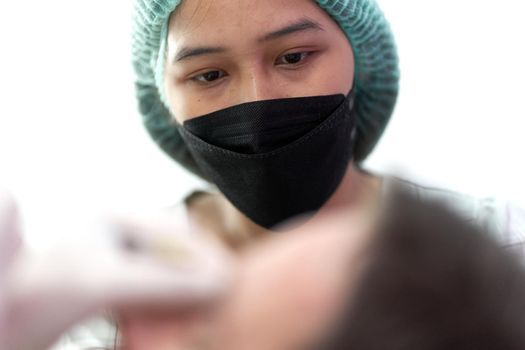 Portrait of a serious nurse looking to a patient that receives a beauty treatment in a clinic