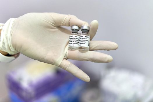 Focus on a hand of a doctor with latex gloves showing two bottles of collagen for facial treatment