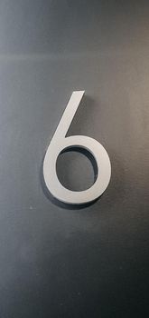 vertical photo of metallic number six on gray wall