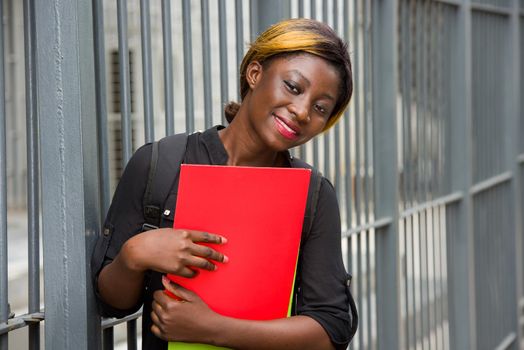 student standing near grid with documents looking at something smiling.