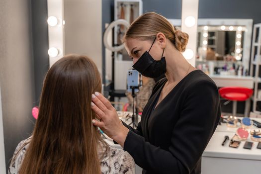 Make-up artist working with brush on model eyes Close up of applying make up on young girl,semi profile, professional make up in beauty studio.