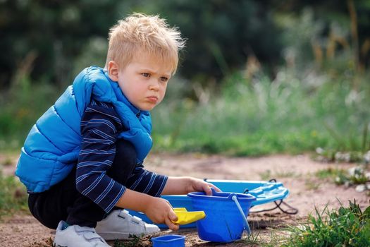 Three year old boy play with sand. Summer outdoor activity for kids.