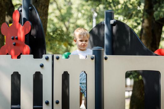 A brave, blond boy plays the captain of a ship in an oak park playground, he is on board.