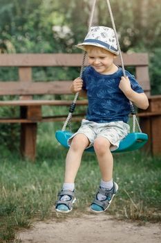 Smiling boy swinging on a rope at a playground.