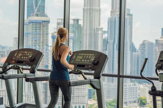 sport, fitness, lifestyle, technology and people concept - woman exercising on treadmill in gym against the background of a big city.