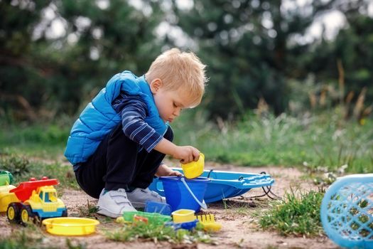 Cute smiling little boy playing with sand toys. Child play in nature on summer family vacation.
