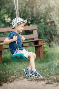 Cute little boy having fun on a playground outdoors in summer garden. Summer outdoor leisure for kids.