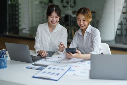 financial, Planning, Marketing and Accounting, portrait of Asian woman Economist using calculator to calculate investment documents with partners on profit taking to compete with other companies.