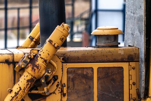 A closeup photograph of an old large industrial yellow bulldozer machine weathered, rusty and worn sitting on a beach in Chicago.