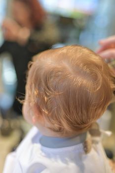 One year old boy for the first time at the hairdresser. First haircut.