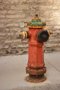 A vintage red metallic fire hydrant in the ground for fighting urban fires.