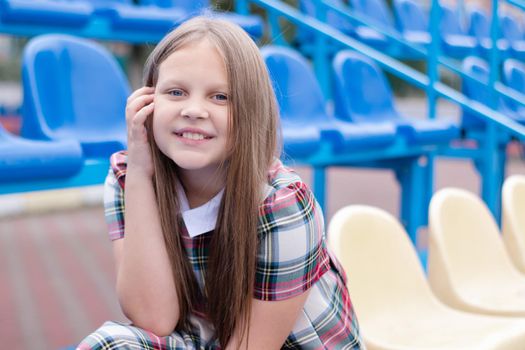 Stadium tribune. tweet brunette girl in dress near Tribunes and plastic colorful chairs in the sports stadium