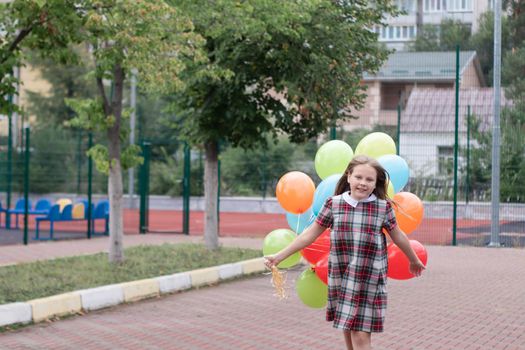 charming teenage girl in checkered brown dress with bunch of colorful balloons. school girl. pretty tween.