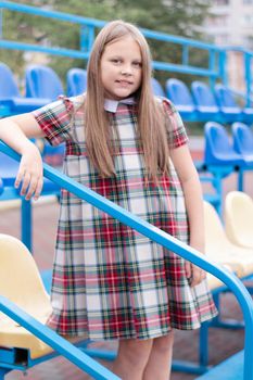 Stadium tribune. tweet brunette girl in dress near Tribunes and plastic colorful chairs in the sports stadium