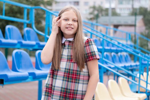 Stadium tribune. tweet brunette girl in dress near Tribunes and plastic colorful chairs in the sports stadium