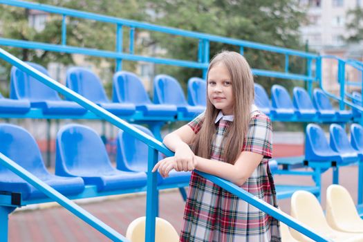 Stadium tribune. tweet brunette girl in dress near Tribunes and plastic colorful chairs in the sports stadium