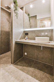 Sinks with mirrors located near shower box with glass door in modern bathroom with white tiled walls